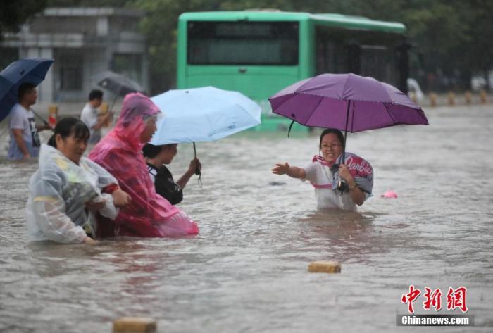 7月20日，鄭州遭遇強(qiáng)降雨，在經(jīng)三路、農(nóng)業(yè)路上，市民互相幫助走在齊腰深的積水里。 圖片來源：視覺中國